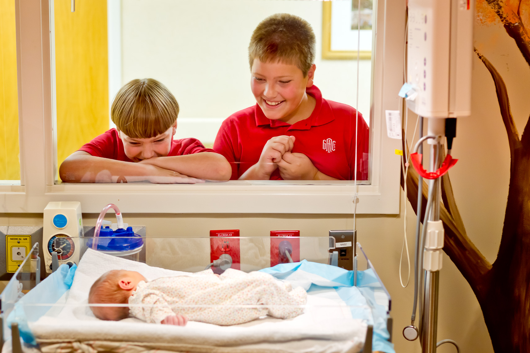 Advertising Photo of Brothers Smiling at Newborn Baby